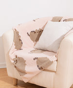 Pusheen Blanket draped over a cream arm chair with a pillow on top.