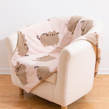Beige armchair with a blanket featuring a repeating pattern of Pusheen the Cat.