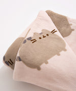 Pusheen Blanket draped over a cream arm chair with a pillow on top.