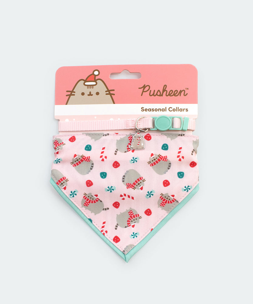 Pusheen Pet Holiday collar and bandana set in packaging that states that the set are seasonal collars. The Pusheen eating a candy cane charm and bandana pattern are displayed at the front. 