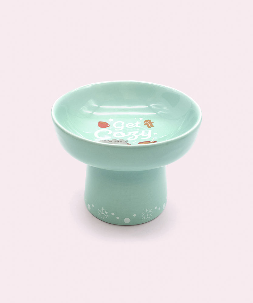 Alternate view of Holiday cat bowl. The bowl features a repeating pattern of white snowflakes on the base of the pedestal.