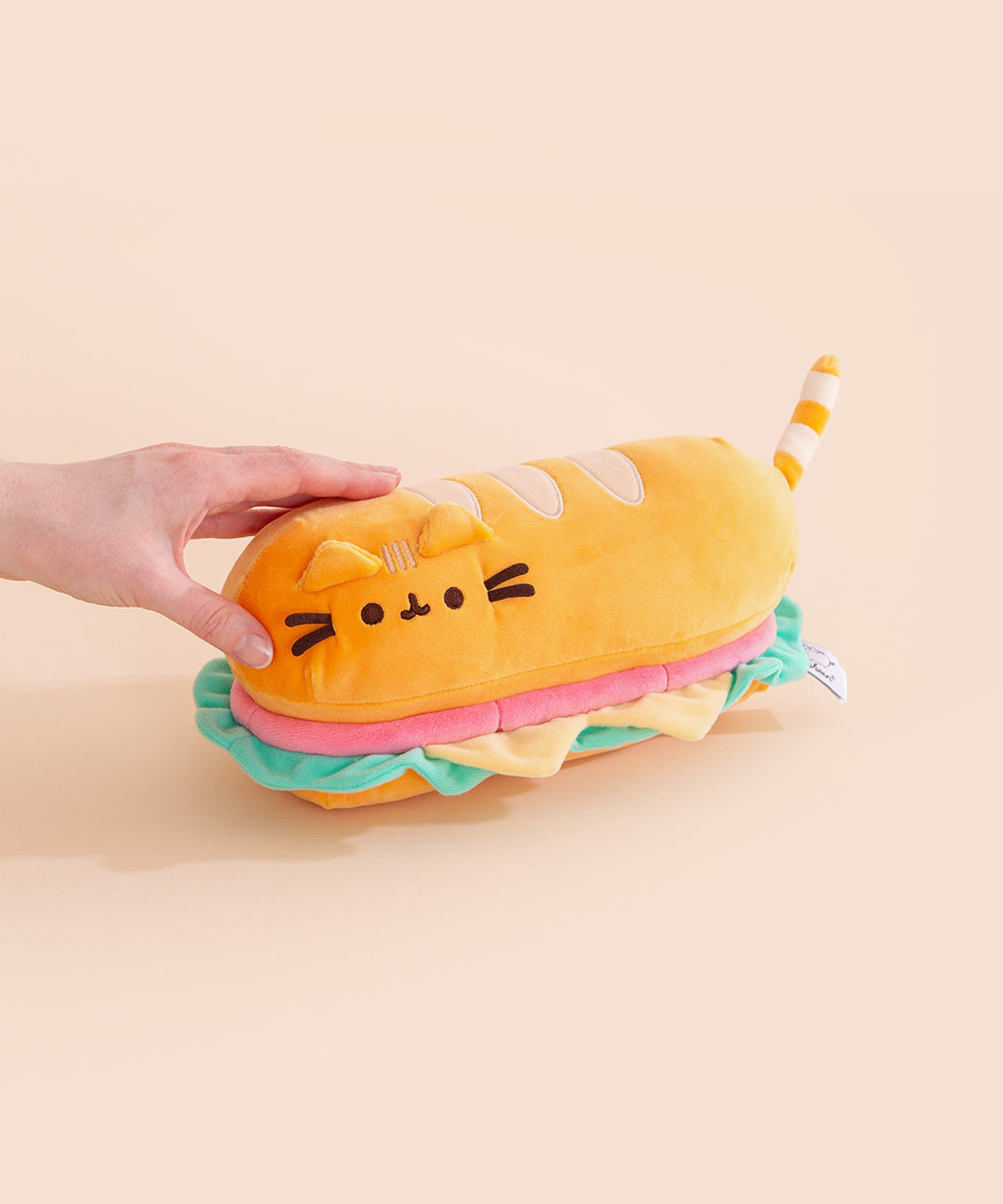Model holds one side of the baguette sandwich plush to show the size and scale of the sub.
