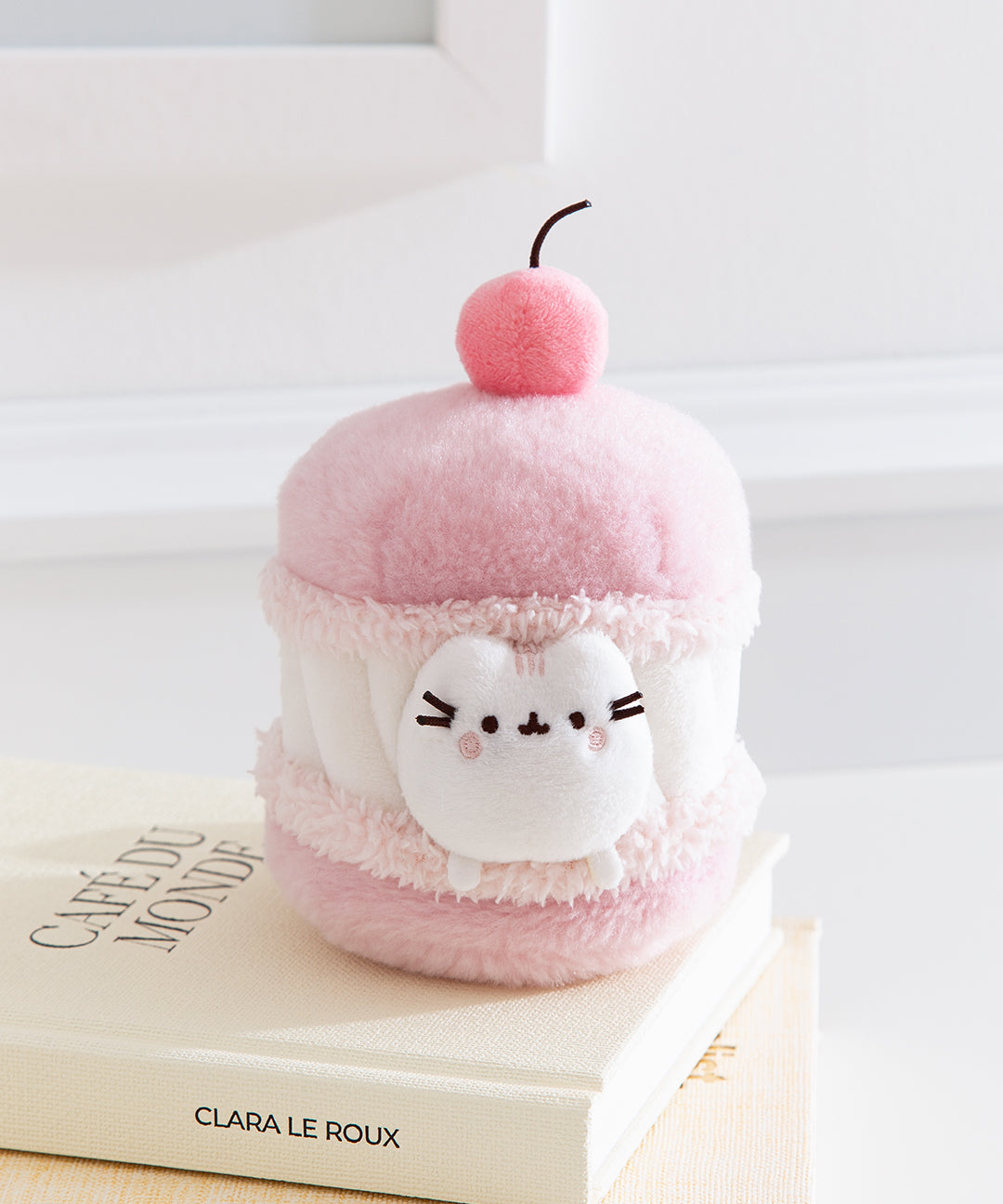 Front view of the Cherry Macaron Pusheen Plush. The pink and white plush environment mimics the look of a macaron with whipped white filling.  