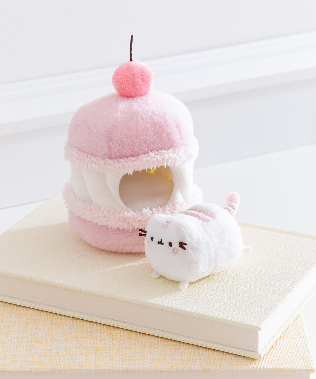 Side view of the Cherry Plush. The removable interior plush rests in front of the cake environment. The little white plush fits inside the front hole of the macaron plush.