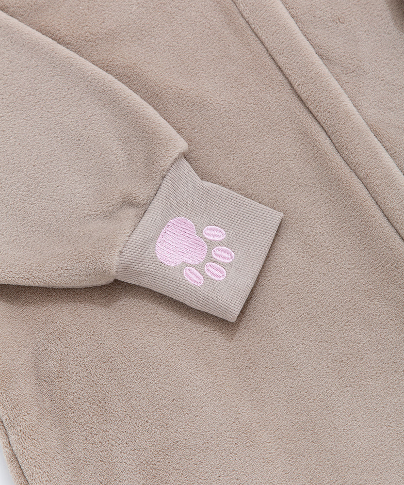 Close-up of a embroidered pink paw print on the expanded ribbed cuff of the brown onesie.