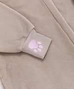 Close-up of a embroidered pink paw print on the expanded ribbed cuff of the brown onesie.