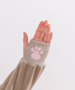 Model's hand with thumb through thumb hole on the Toe Beans Kigurumi. A pink paw print is embroidered on the ribbed cuff.