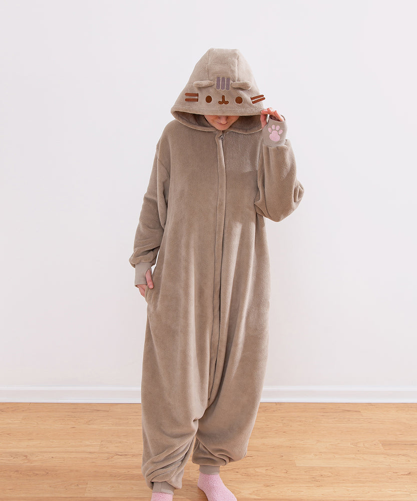 Model wearing a brown Pusheen Toe Beans Kigurumi onesie with a hood that has Pusheen the Cat's face embroidered on it and has 3D brown whiskers.