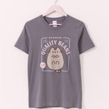 Pusheen Toe Beans Tee hangs on a light pink hanger on a light background. The medium grey tee shirt has a graphic of Pusheen the Cat lying on her back showing off her bottom pink toe beans.