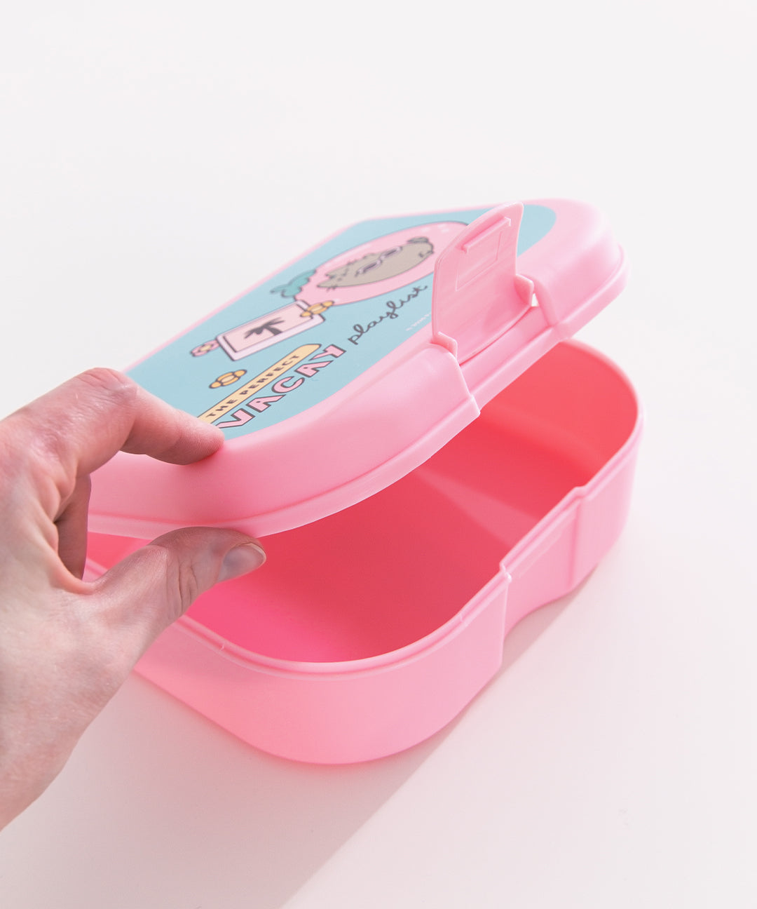 Model holding the top lid open on the Pusheen lunch box. The secure closure clasp is located at the front side of the box.