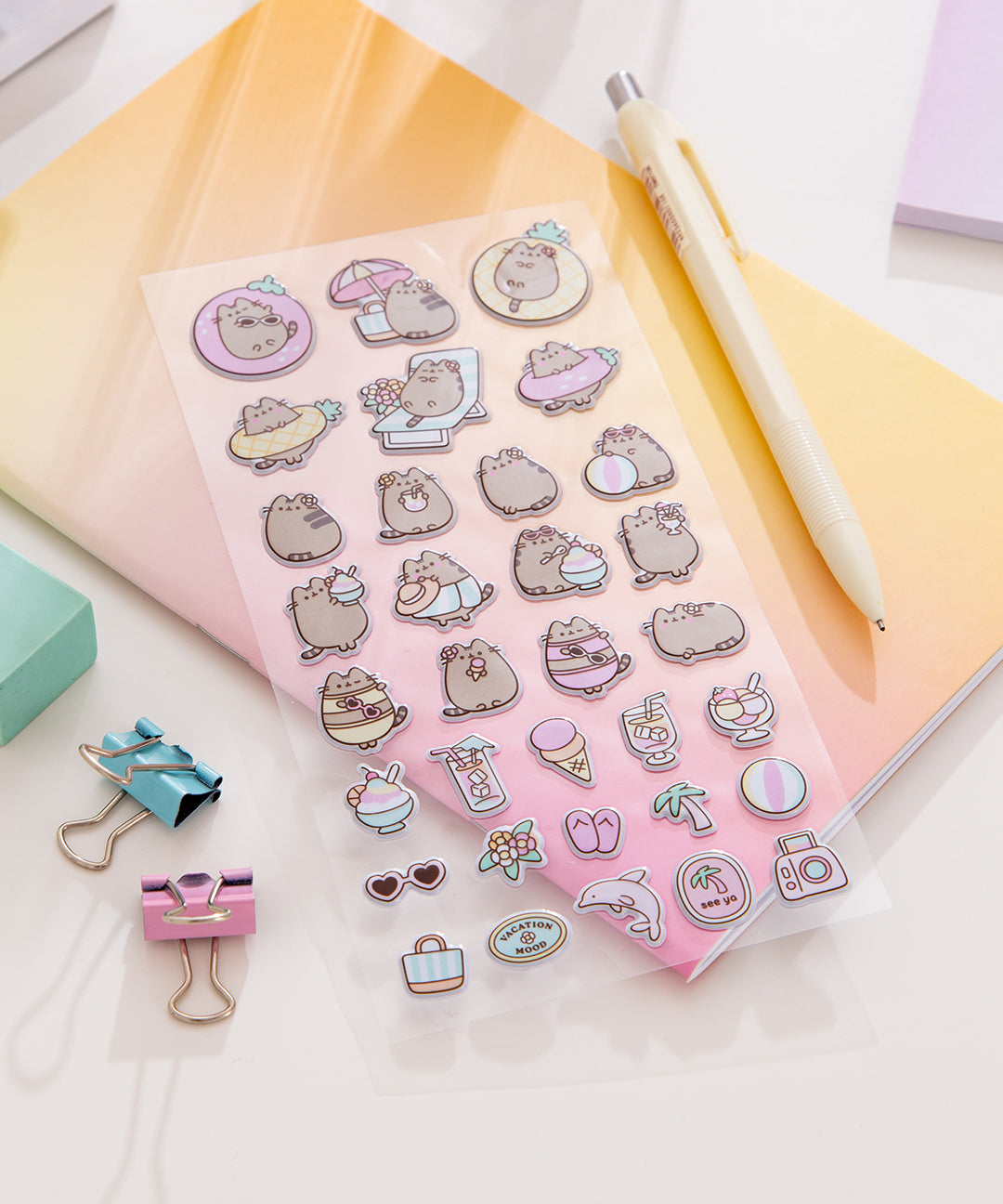 Close-up of the sticker sheet of Pusheen enjoying her tropical vacation with treats and lounging essentials like sunglasses.