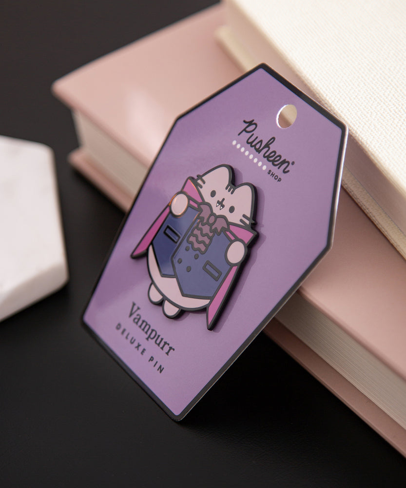 Pusheen Vampurr Deluxe Pin tilted to the side to shown the shiny black outline of the pin.
