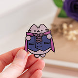 Model holding the Vampurr Deluxe Pin. Pusheen the Cat is shown wearing a waist coat, bowtie, and cape. The cat has two fangs shown outside of her mouth.