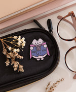 Halloween vampire pink on a black eyeglass case to show the size and scale of the deluxe pin.