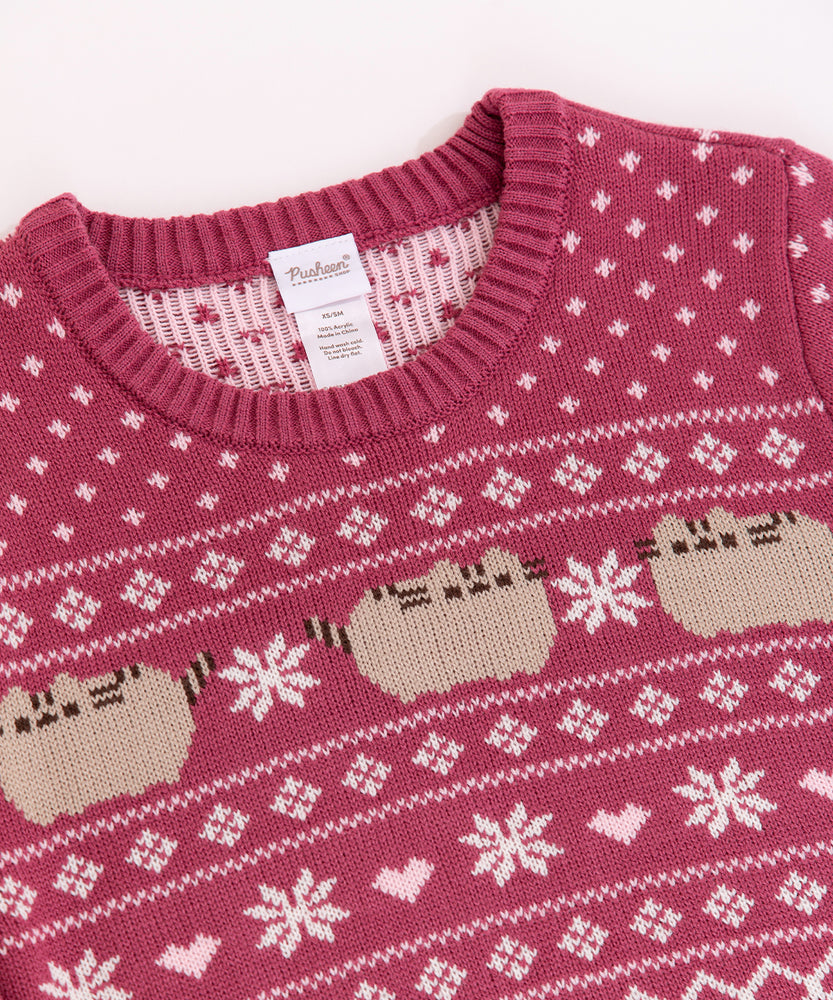 Close-up of the front knit pattern on the  Pusheen Holiday Sweater. The repeating pattern shows Pusheen the cat with white snowflakes and baby pink heart details.