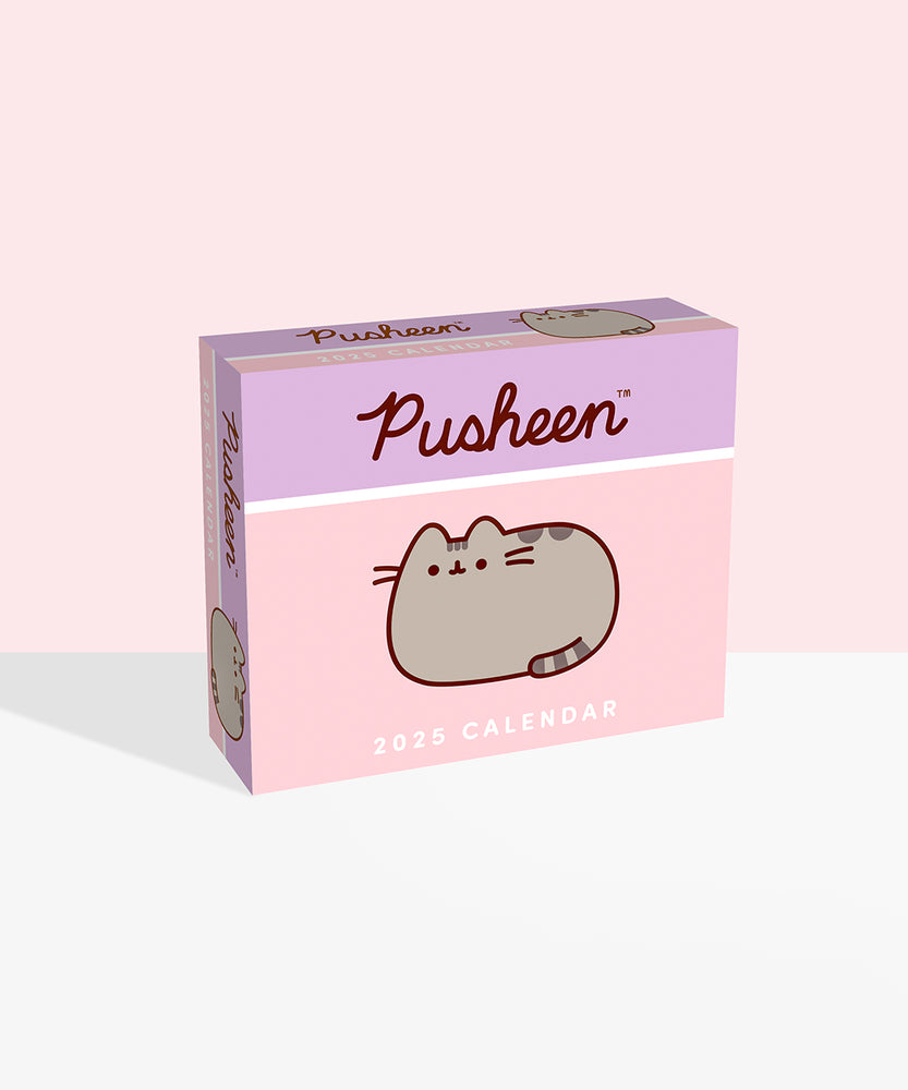 Front view of the box of the Pusheen 2025 Daily Desk Calendar. The purple and pink box has a graphic of Pusheen the Cat on the front. Inside is a stack of paper calendar pages that feature artwork of  Pusheen, her friends, and her siblings to document each day and holiday.