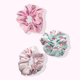 Top-down view of the Pusheen Hair Scrunchys. The circular hair bands have three unique Pusheen patterns printed on the light pink, mint green, and white hair scrunchies.  