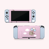 Front and back view of the Pusheen Balloons decal for a Nintendo Switch OLED. The front side is a two-toned light pink and light blue colors with a Pusheen graphic and white fluffy clouds. The back has blue joy stick stickers and a pink middle background with white fluffy clouds and a graphic of Pusheen in the middle of the decal being carried by three balloons.