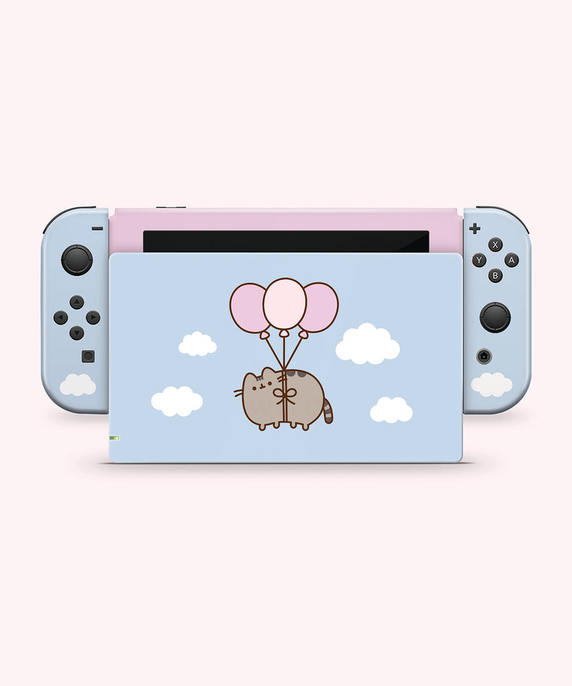 Front and back view of the Pusheen Balloons decal for a Nintendo Switch OLED. The front side is a two-toned light pink and light blue colors with a Pusheen graphic and white fluffy clouds. The back has blue joy stick stickers and a pink middle background with white fluffy clouds and a graphic of Pusheen in the middle of the decal being carried by three balloons.