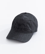   Left quarter view of Pusheen Black Denim Cap lying on a white surface. The black hat brim points towards the bottom left corner. The hat seams are in a black thread to match the charcoal hat color. 