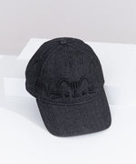 Top-down view of the Pusheen Black Denim Cap. The top button and seams can be seen from this view as well as the thread detailing on the bill of the hat. The hat is propped on a white box to show the full size of the baseball-style cap. 