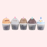 Line up of the Pusheen Boba Tea Surprise Squishy styles. From left to right is a yellow Sloth, light gray little sister Stormy, a gray Pusheen the Cat, a dark grey little brother Pip, and a blue and white Bo the Parakeet.
