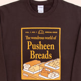 A close-up view of the screen-printed graphic of the Pusheen Breads Unisex Sweatshirt. The golden, magazine-style graphic features Pusheen Breads in bakery case surrounded by a golden, rectangle border.  