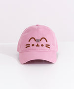 Front view of the pink Pusheen Cap. The light mauve baseball-style hat has Pusheen the Cat’s face embroidered in a 3D effect. The brown and grey thread is on the front center of the cap. 