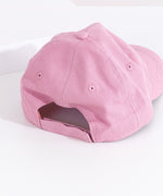 Back view of the light mauve hat. The baseball style cap has a top button, eyelet holes for head ventilation, and an adjustable Velcro strap on the back for customized fit. 