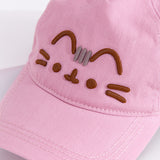 Close up view of embroidered graphic on the front center of the baseball style cap. Pusheen the Cat’s ears, eyes, mouth and whiskers are shown in brown embroidered thread while her head whiskers are shown in a light grey thread color. 