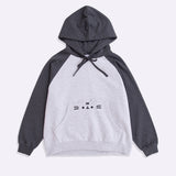 Pusheen Character Loungewear Hoodie lies on a flat surface. The two-toned sweatshirt features Pusheen’s face on the front pocket of the hoodie. The hood and sleeves are dark grey and the chest and bottom of the sweatshirt are light gray. 