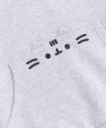 A close-up view of the embroidered graphic on the front pocket of the sweatshirt. The classic Pusheen pose shows her whiskers, mouth, eyes, head stripes in a dark gray thread. The cat’s rounded triangle ears are made of the same fabric as the hoodie and are a 3D feature of the hoodie. 