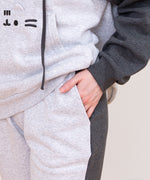 Close-up view of a model wearing the Pusheen set. The model has their hand in the side pocket. The two-toned of the sweatshirt and joggers can be seen in this image.