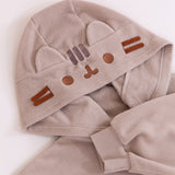 Close up of the embroidery of Pusheen's face on the classic kigurumi hood. The hood also features cat ears made of the same material as the kigurumi, and brown felt whiskers. Under the hood is the hem of the sleeve that has a stretchy ribbed cuff. 