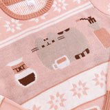 Close-up of the front knit pattern on the Coffee-themed Pusheen Sweater. The grey cat is lying next to a coffee mug, a drip coffee maker, and coffee grinder. 