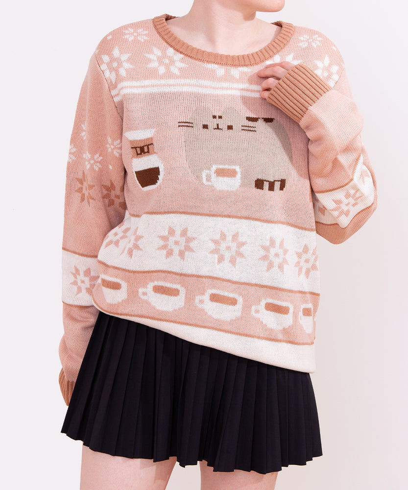 Light-brown and medium-brown knit sweater lies on a white background. The sweater has graphics of Pusheen the Cat and coffee making items.