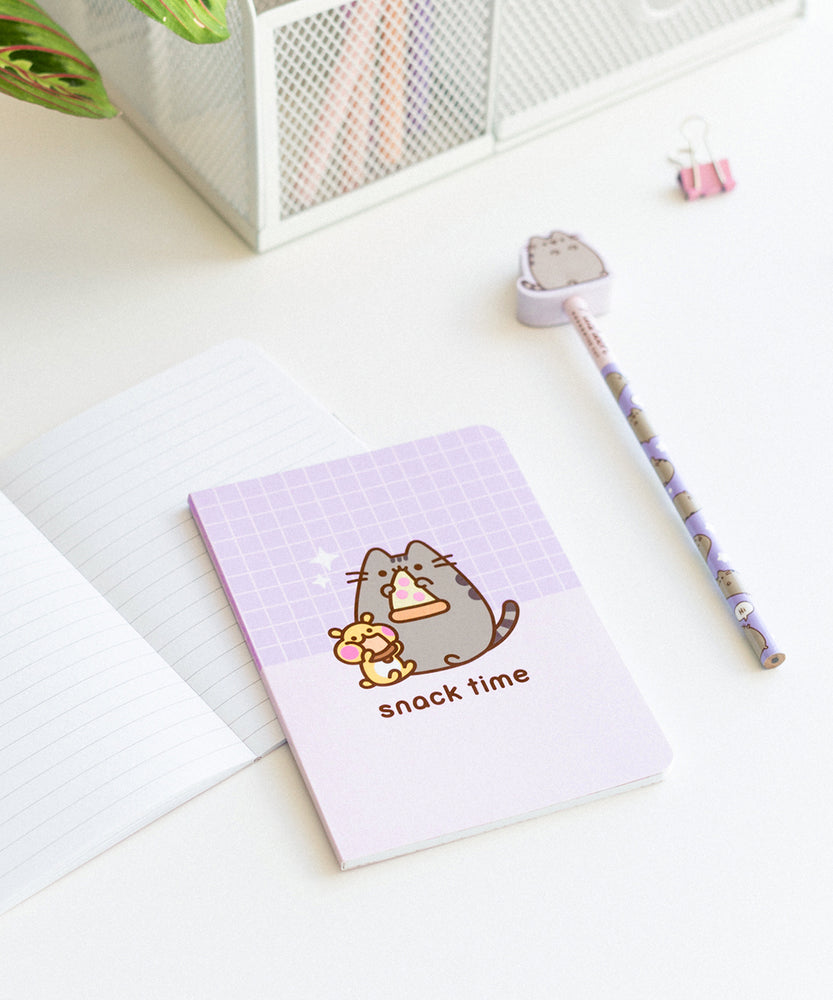 Included notebook, pencil, and eraser topper laid out on a desk. The purple office accessories showcase various graphic of Pusheen the Cat.