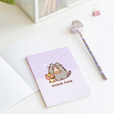 Included notebook, pencil, and eraser topper laid out on a desk. The purple office accessories showcase various graphic of Pusheen the Cat.