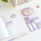 Notebook and included sticky note tabs in the Pusheen Deluxe Stationery Set. The purple and pink tabs include various Pusheen graphics as well as Stormy.