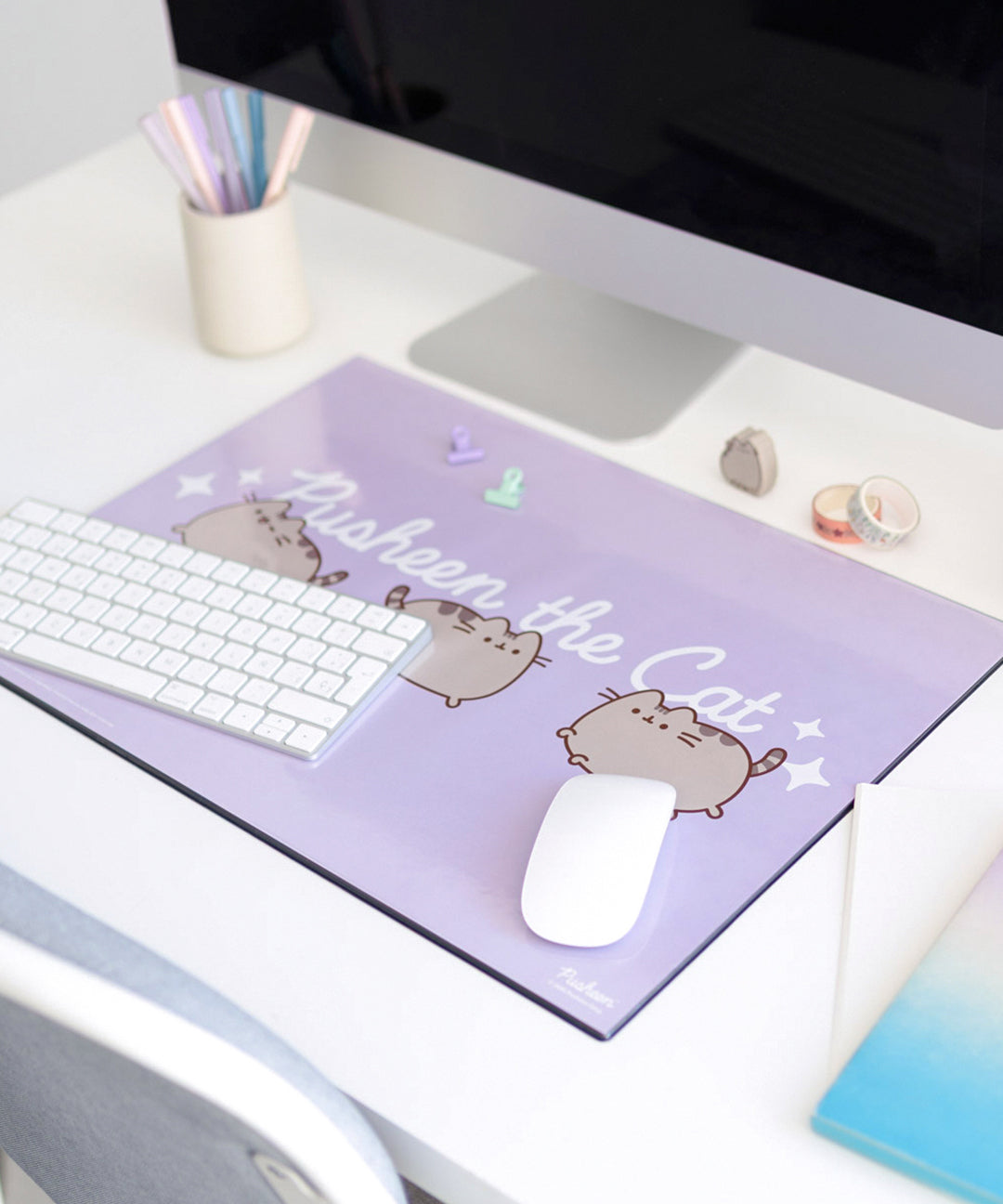 Pusheen Desk Mat shown with a keyboard and mouse to demonstrate the size and scale of the purple laminated mat.