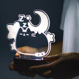 Model holding Pusheen Lamp to show size of lamp. The cat is surrounded by stars, a crescent moon, and zz's. The cat body gives off a light purple glow.