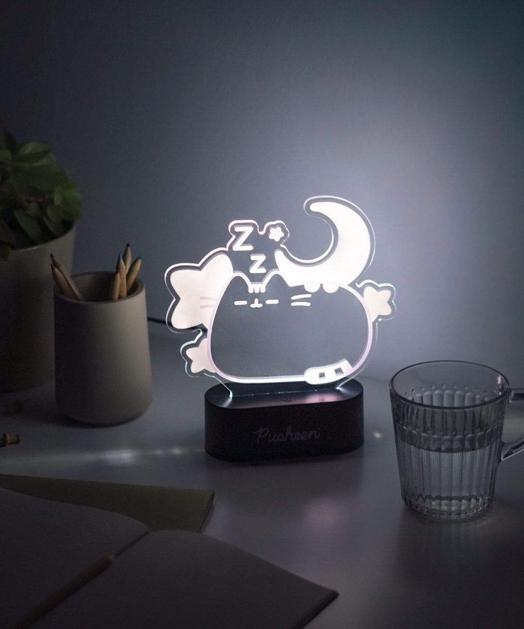 Front view of the dreams Pusheen lamp lit up. The clear acrylic cat body emits a white hue when turned on.  