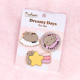 The pin set is attached to a cardboard backing featuring white fluffy clouds on a light pink background. The pin set is lying on a white light pink background. 
