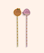 Pencils and erasers in the Pusheen Fruits 2-Pencil Set. The full-length pencils include and all over print of Pusheen as peaches and oranges on orange and pink checkered pencils. Atop the pencils are the included erasers or Pusheen taking the form of an orange and a pink and yellow peach.