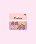 Pusheen Fruits 4-Pack Stud Earrings Set on their cardboard backing card. The top half of the card has the Pusheen logo in brown on a light pink background and the bottom half of the card is purple. 