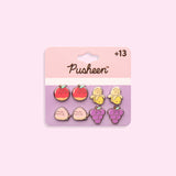 Pusheen Fruits 4-Pack Stud Earrings Set on their cardboard backing card. The top half of the card has the Pusheen logo in brown on a light pink background and the bottom half of the card is purple. 
