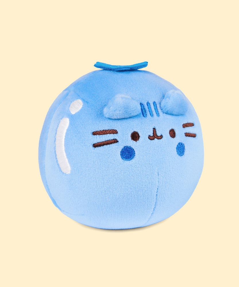 Back view of the Pusheen Fruits Blueberry Squisheen Plush. The back of the blue squisheen has Pusheen’s signature back stripes duo embroidered in dark blue. Under the stripes is Pusheen’s striped tail in alternating blue colors. Coming off the top of the plush is a blue felt calyx. 