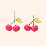 Front view of the Pusheen Fruits Cherry Dangle Earrings. Pusheen the Cat takes the form of ripe red cherries held together by a green stem and accented with a light green leaf.  
