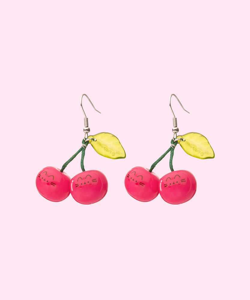 Pusheen Fruits Cherry Dangle Earrings on their cardboard backing card. The top half of the card has the Pusheen logo in brown on a light pink background and the bottom half of the card is purple. 