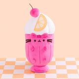 Front view of the Pusheen Fruits Fruit Parfait Plush. Pusheen the Cat takes the form of a delightful dessert served with a whipped topping, hot pink cherry, and orange slice. The whipped topping is white and extends off the glass-shaped body. 